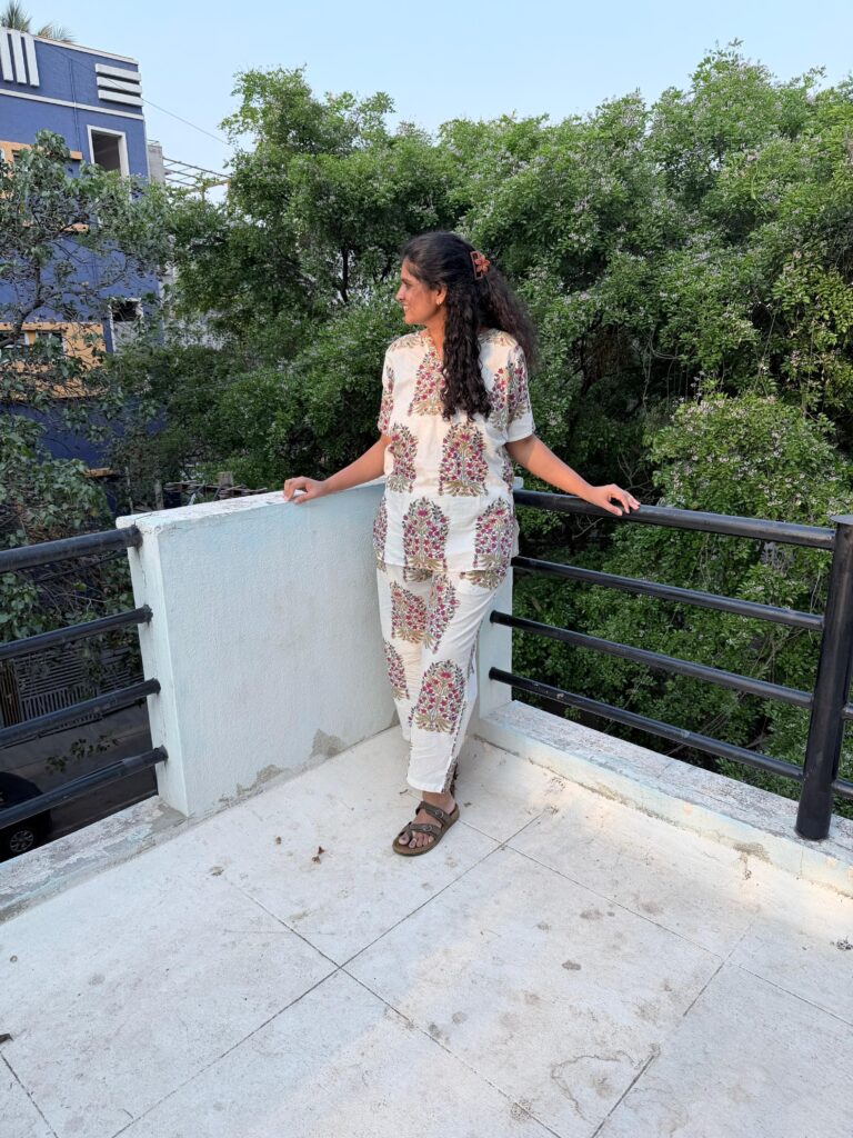 A smiling woman relaxaing, showcasing premium home textiles and cozy lifestyle apparel from Taniroop.